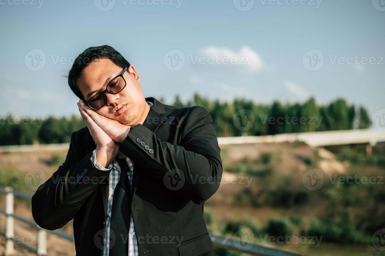 homme d'affaires asiatique fatigué et dormant pour se détendre à l'extérieur photo