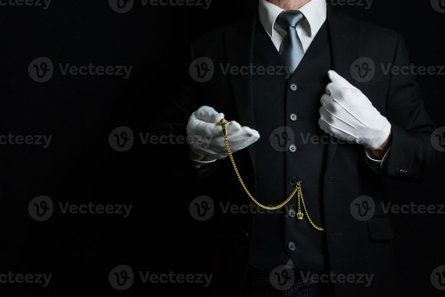 portrait de majordome en costume sombre et gants blancs tenant une montre de poche en or. style vintage et courtoisie professionnelle. photo