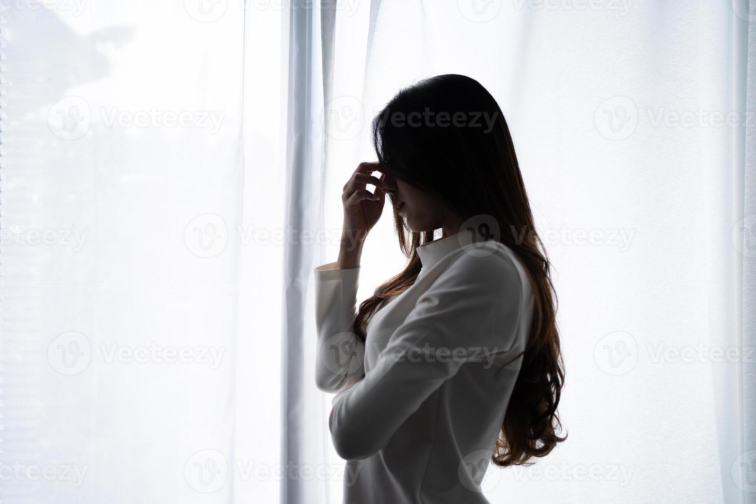 jeune femme asiatique stressée souffrant de dépression et se tenant seule dans une pièce sombre à la maison. concept déçu photo