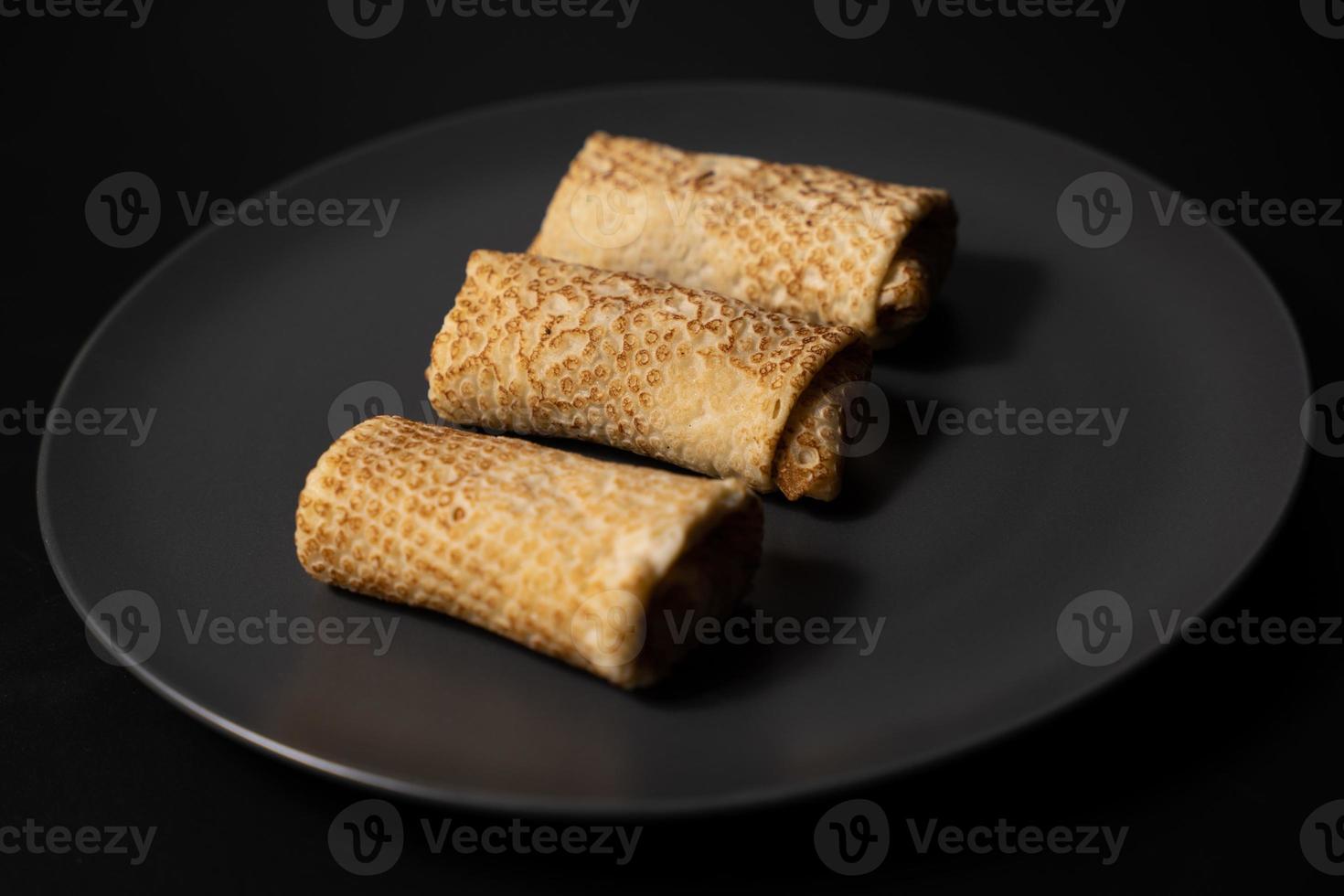 crêpes au fromage sur une assiette et ustensiles de cuisine sur fond noir photo