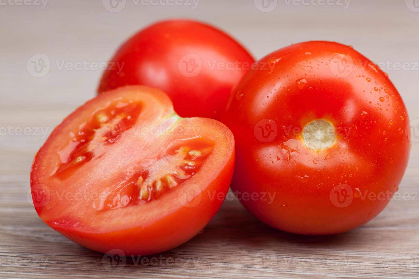 gros plan de tomates fraîches dans des gouttes d'eau sur une planche de bois photo