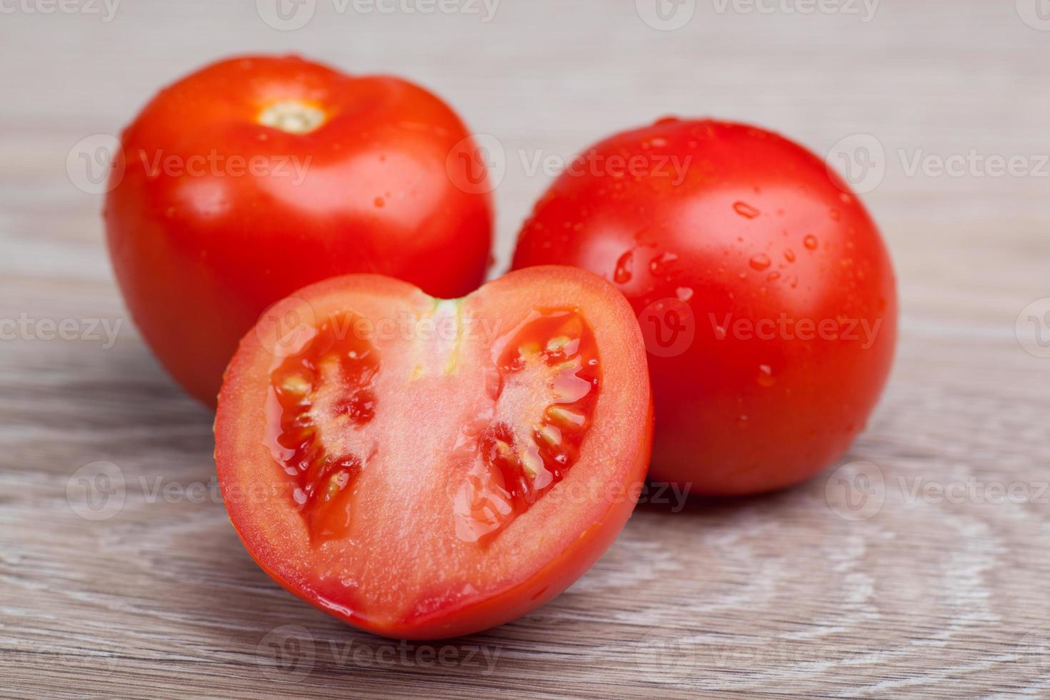 gros plan de tomates fraîches dans des gouttes d'eau sur une planche de bois photo