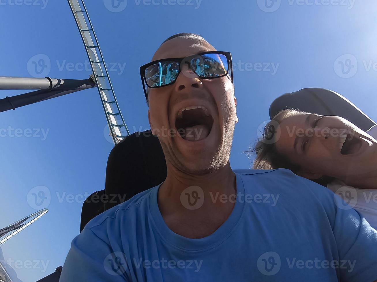 homme et femme sur un tour de montagnes russes avec émotion sur leurs visages. photo