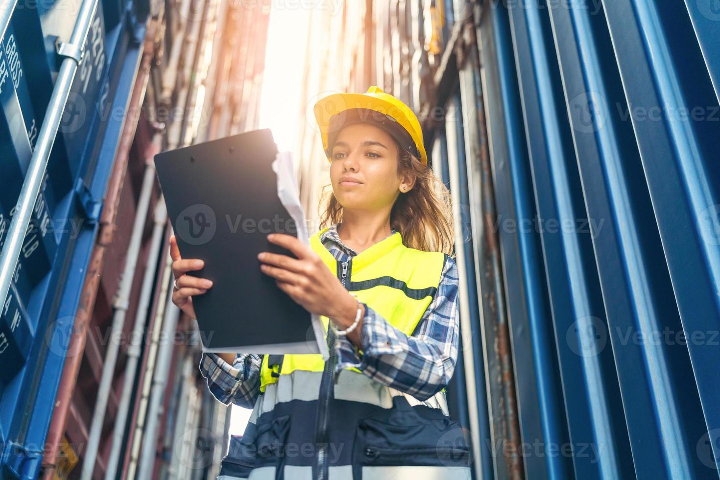 les femmes ingénieures portent des EPI vérifiant le stockage des conteneurs avec un fond de conteneur de fret au coucher du soleil. logistique globale d'importation ou d'exportation concept industriel d'expédition. photo