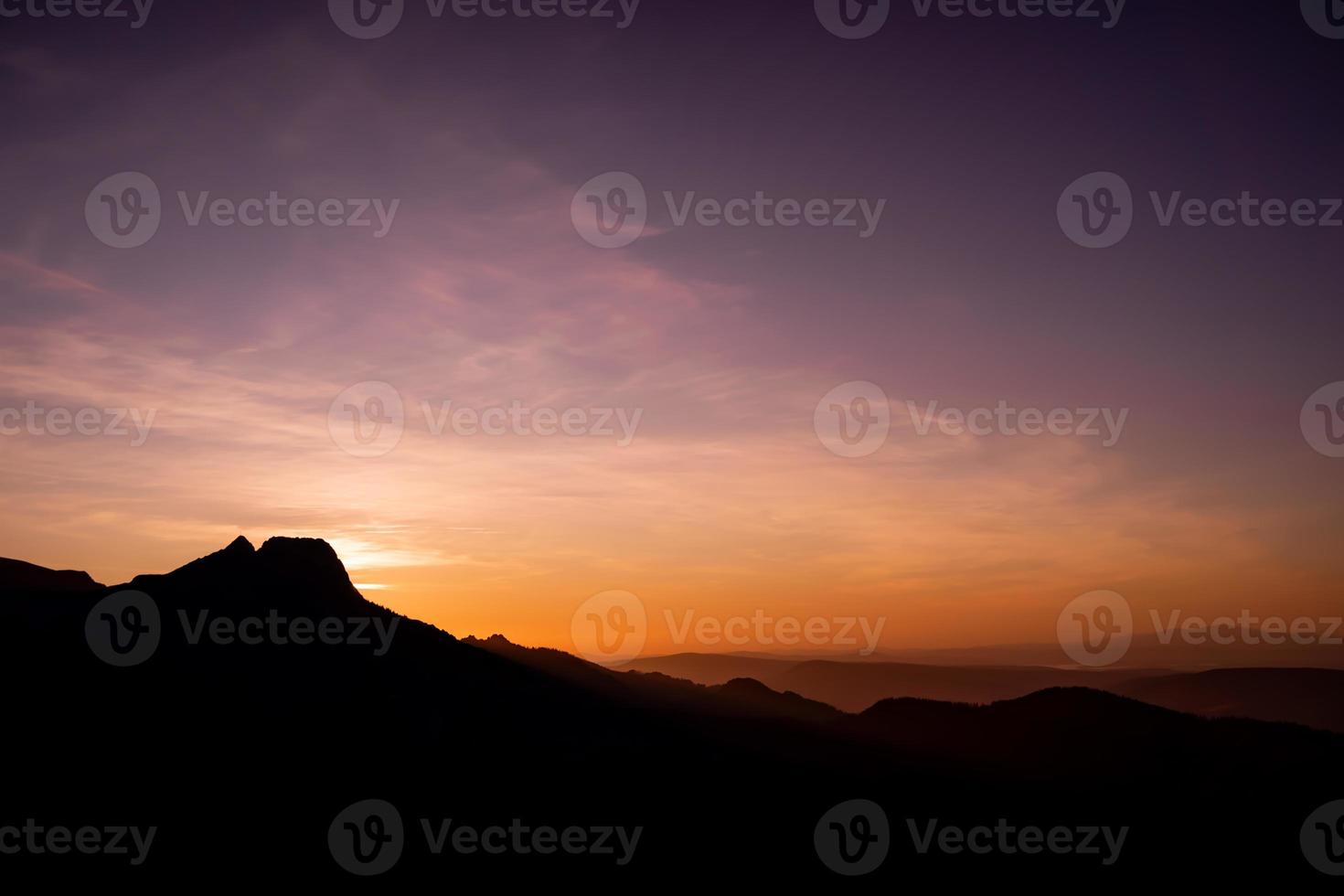 coucher de soleil violet et orange romantique sur les hautes tatras avec une brume dense et de longs rayons de soleil. lever de soleil vibrant et coloré depuis le sommet. trekking pendant l'heure d'or dans la forêt. photo