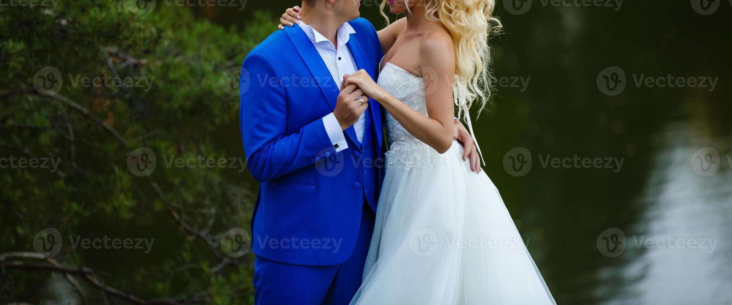 un jeune couple de jeunes mariés dans leurs robes de mariée se tient sur le rocher au bord de l'océan photo