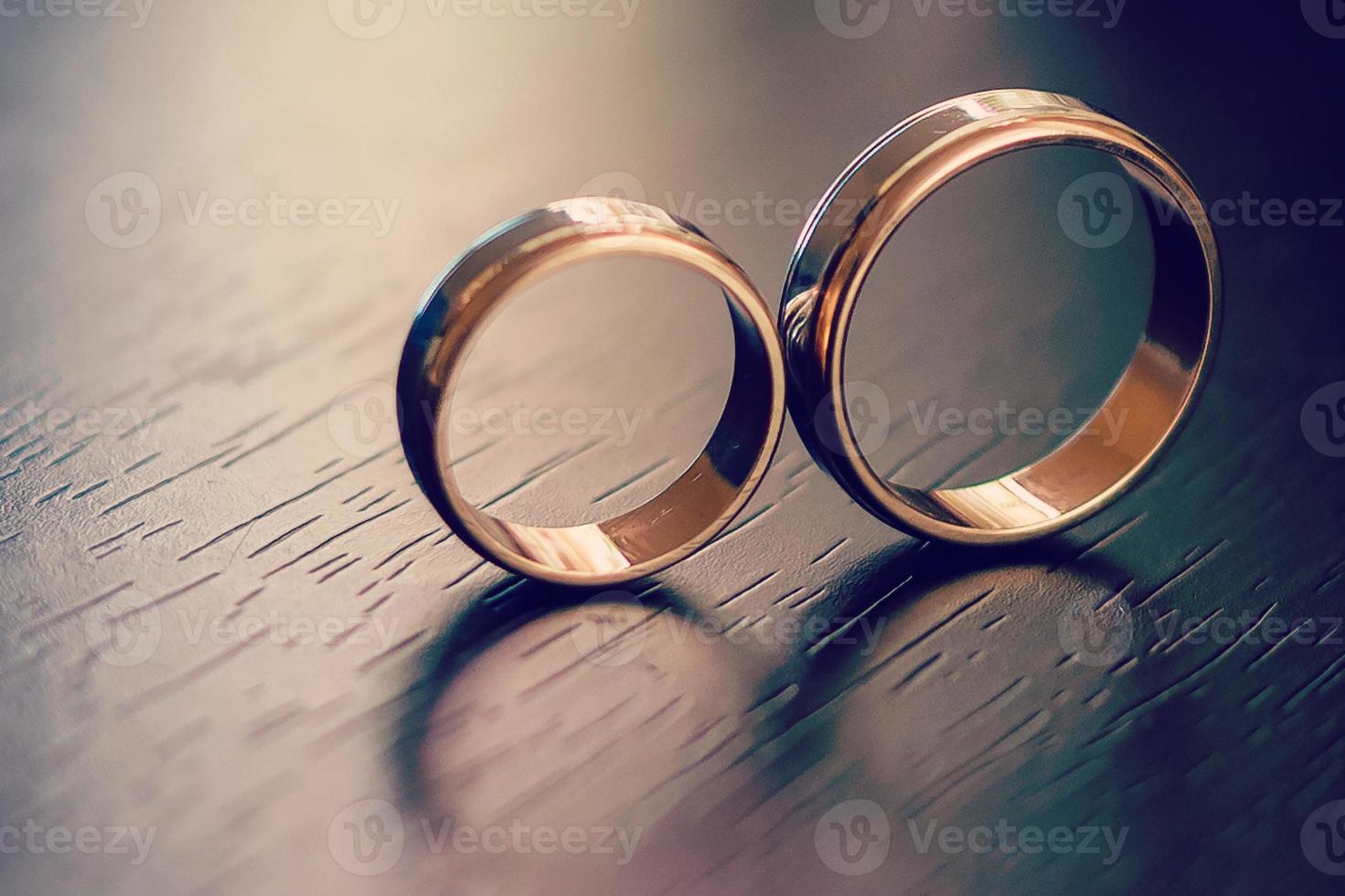 détails de la matinée du jour du mariage. deux alliances en or sont sur la table en bois marron photo