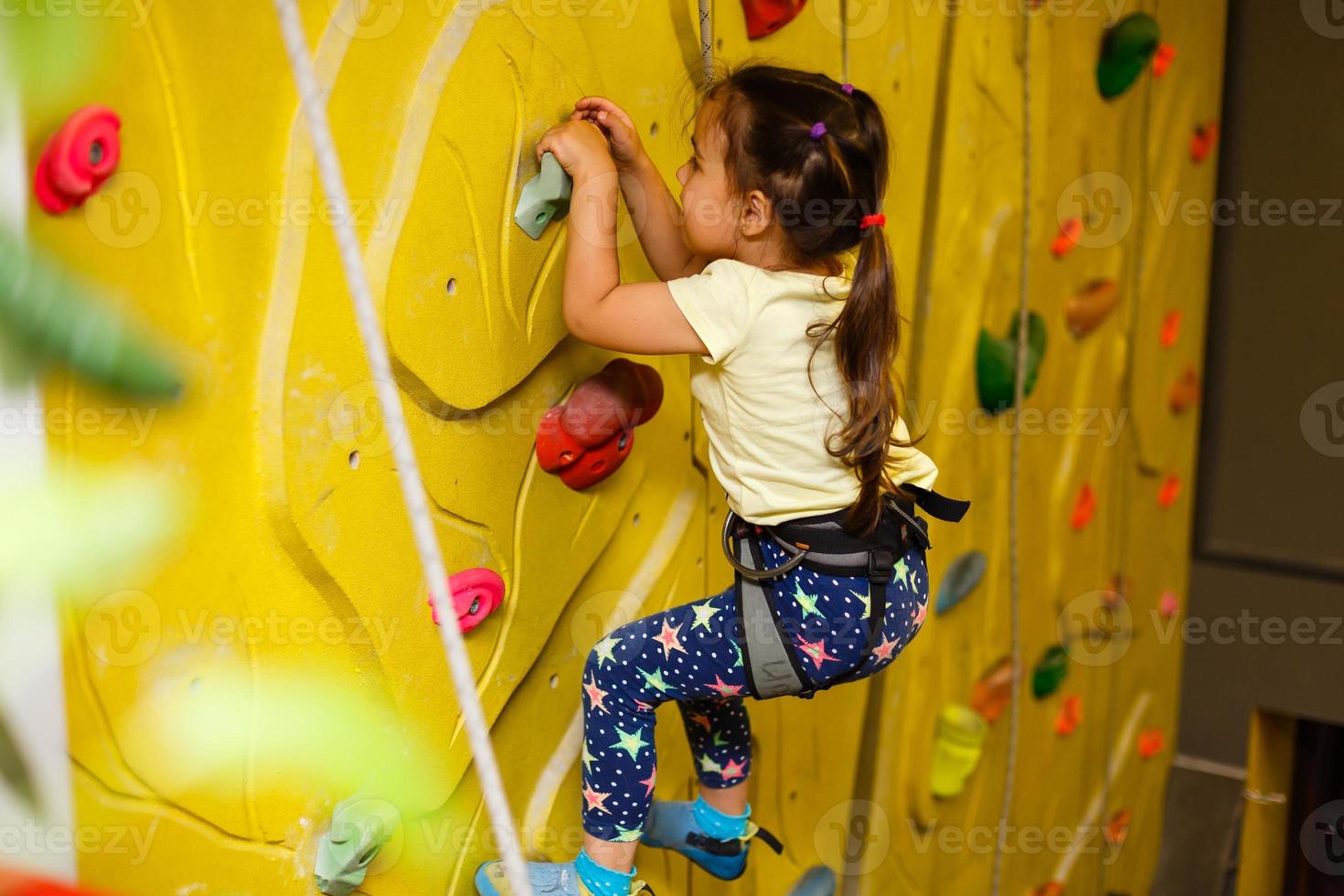 petite fille escaladant un mur de roche à l'intérieur photo