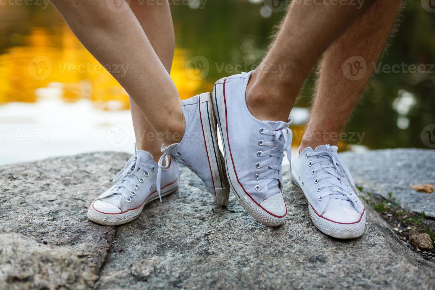 histoire d'amour racontée par des bottes. pieds humains se bouchent. homme et femme en baskets. fille en chaussures blanches. mec en baskets noires et denim. couple hipster en été. jambes se bouchent. photo