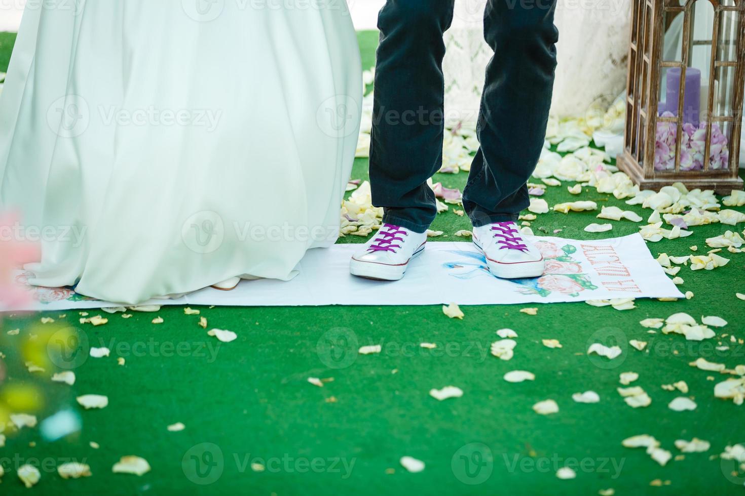 les jeunes mariés se tiennent sur la serviette de mariage rouge photo