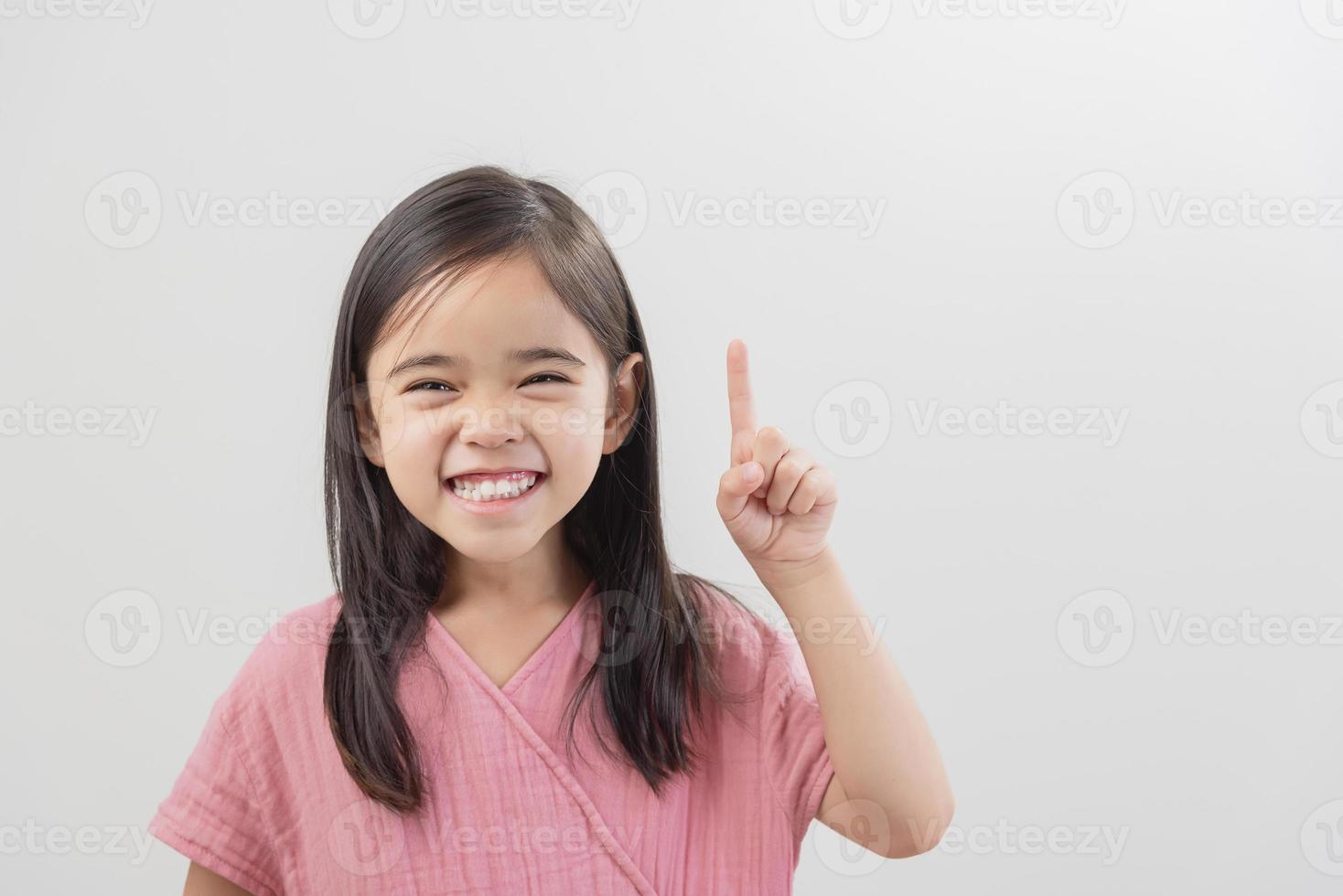 portrait de jolie fille asie aux cheveux longs gesticulant doigt pointé en se tenant debout sur fond blanc photo