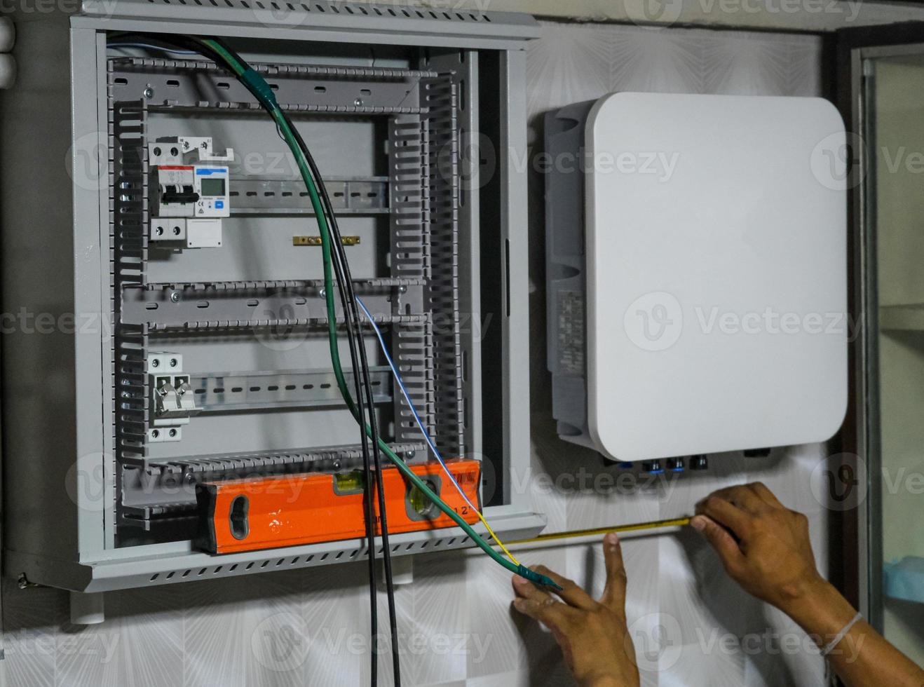 Un homme électrique installe un panneau d'onduleur pour une cellule solaire sur le mur de la maison un technicien d'entretien du système de tension de fil un service pour la sécurité photo