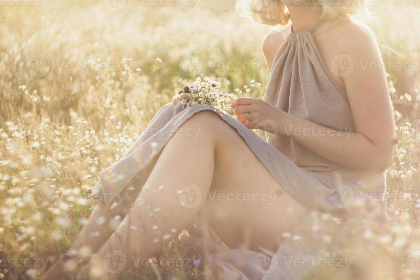 Close up jeune femme avec bouquet assis dans une prairie de fleurs sauvages photo concept