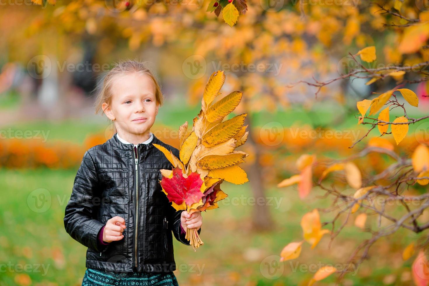 portrait d'adorable petite fille au bouquet de feuilles jaunes à l'automne sur scooter photo