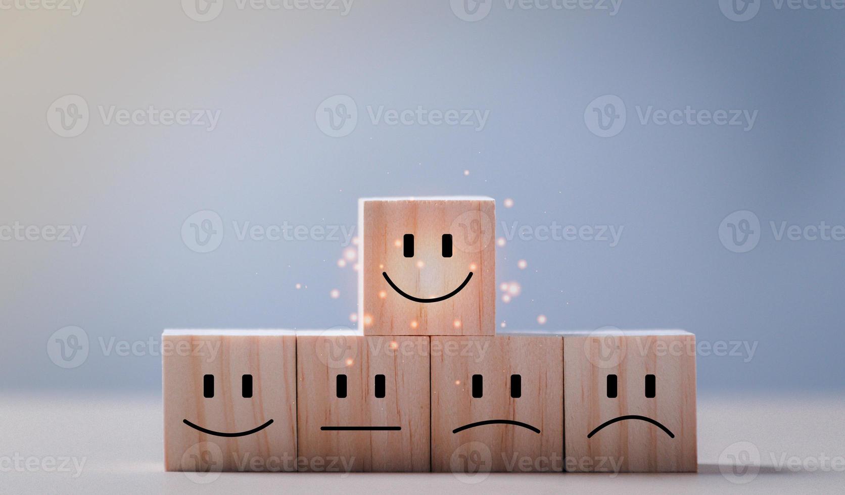 concepts d'évaluation du service client et d'enquête de satisfaction. le visage heureux du client sourire visage icône cube en bois sur la table. photo