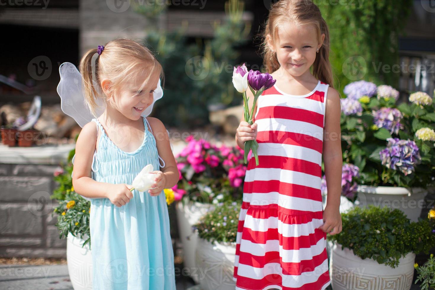 douces petites filles dans une cour de campagne avec des fleurs dans leurs mains photo