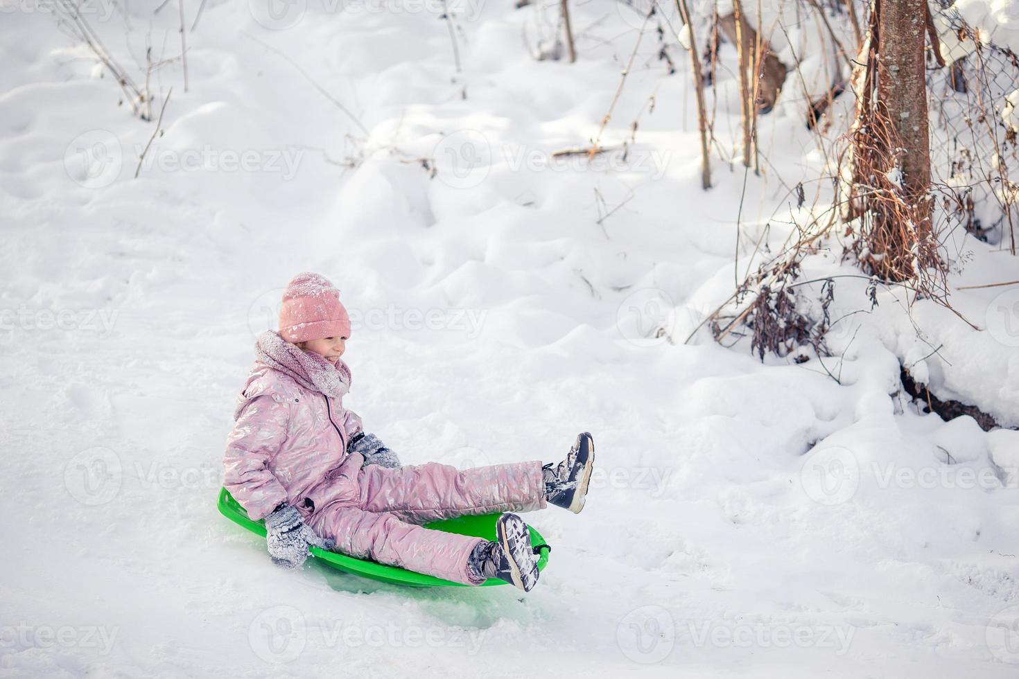 adorable petite fille heureuse faisant de la luge en hiver neigeux. photo