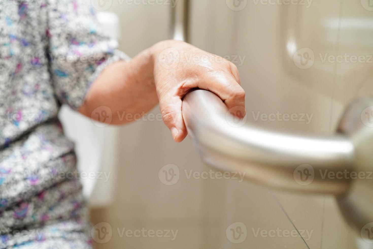 une vieille femme asiatique âgée utilise un rail de support de toilette dans la salle de bain, une barre d'appui de sécurité pour main courante, la sécurité dans l'hôpital de soins infirmiers. photo