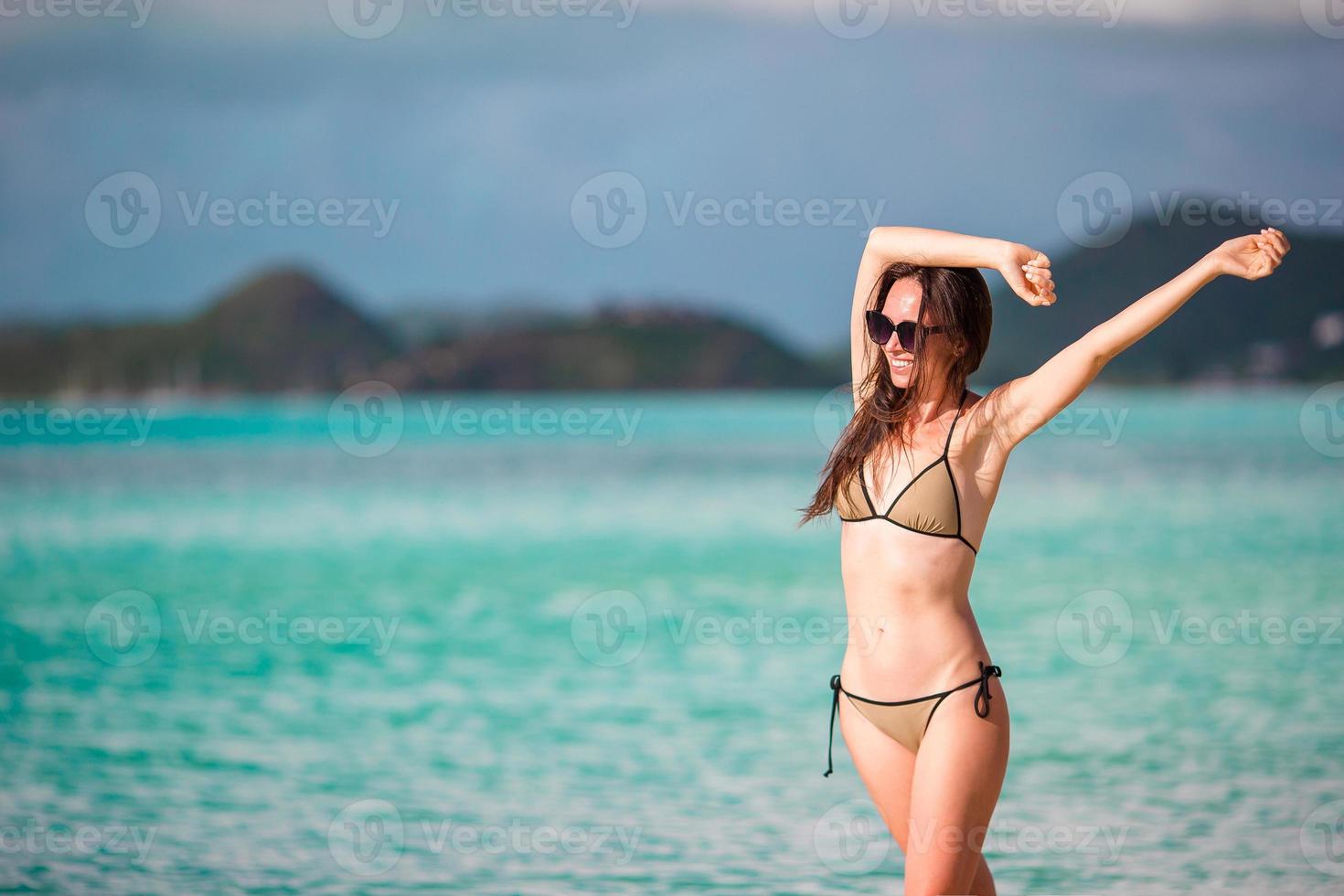 personnes de vacances à la plage - femme regardant un paradis parfait avec de l'eau de mer turquoise en vacances dans les Caraïbes. fille en bikini prenant un bain de soleil pendant les vacances de voyage sur l'île de luxe. photo