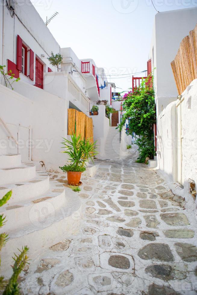 les rues étroites avec des balcons bleus, des escaliers, des maisons blanches et des fleurs dans un beau village en grèce. belle architecture d'extérieur de bâtiment de style cycladique à mykonos photo