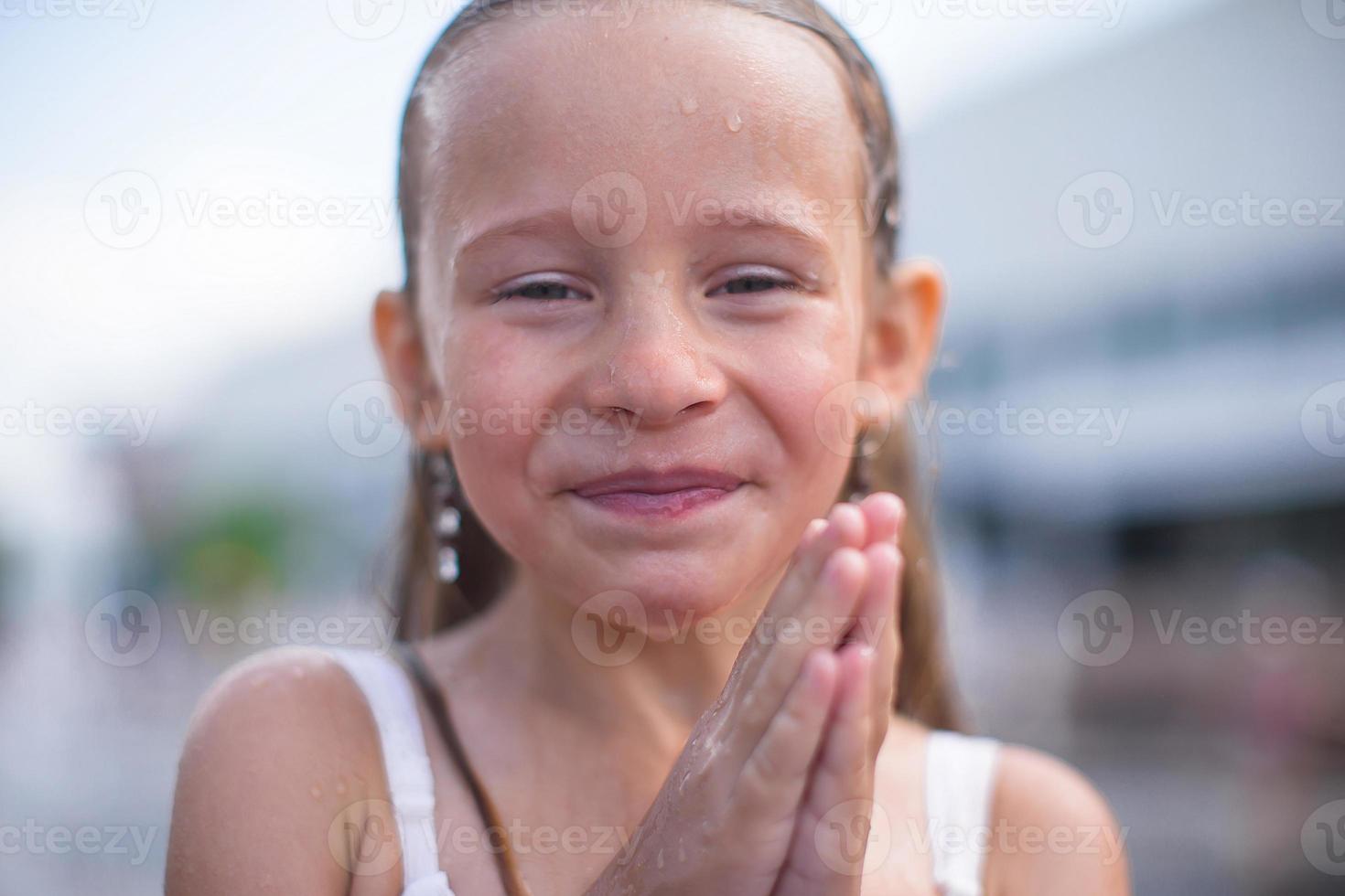 portrait de petite fille heureuse dans une fontaine en plein air photo