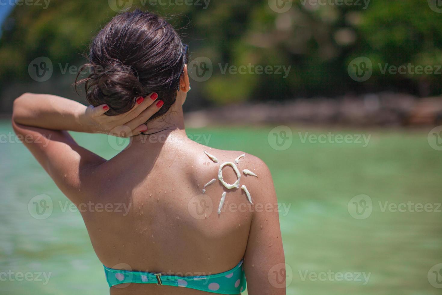 soleil fait avec de la crème solaire à l'épaule de la femme photo