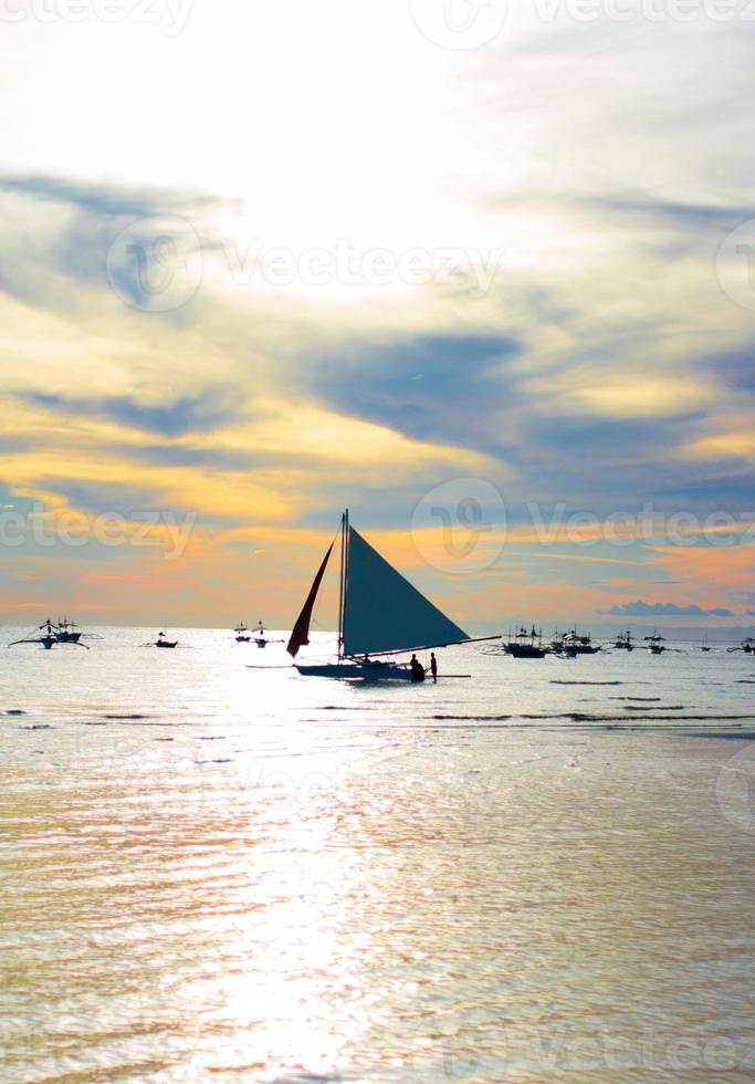 bateau à voile au beau coucher de soleil coloré photo