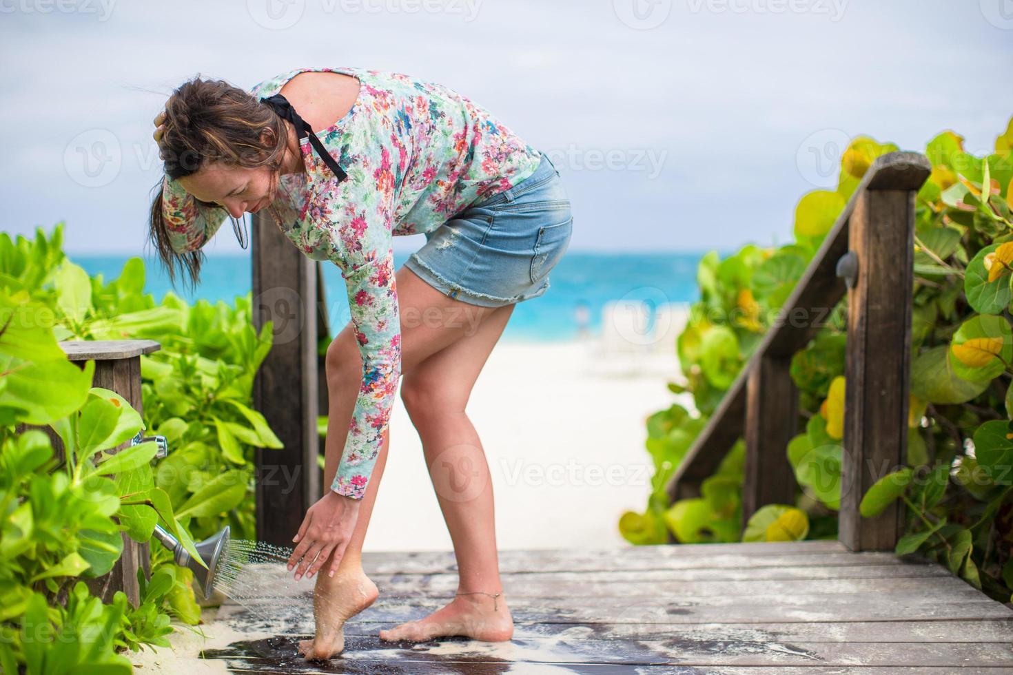 jeune femme lave le sable de ses pieds sur la plage blanche photo