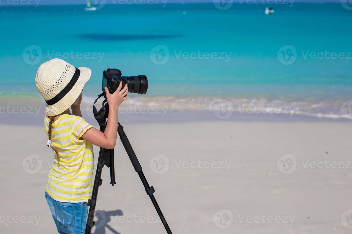 petite fille prenant des photos avec un appareil photo sur un trépied pendant ses vacances d'été