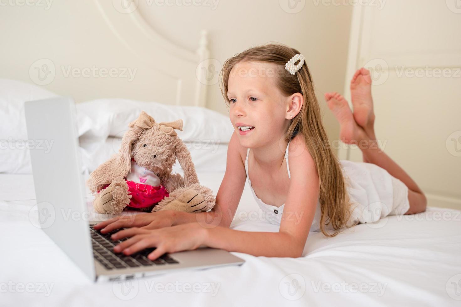 jolie petite fille faisant ses devoirs sur un ordinateur portable photo