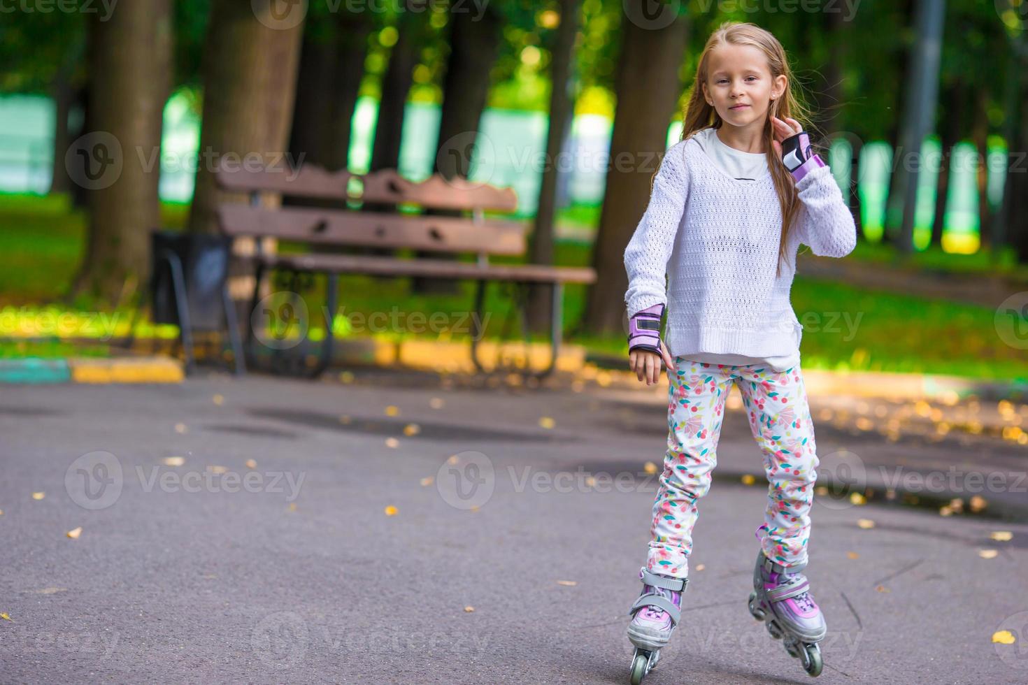 petite fille en patins à roulettes dans un parc photo