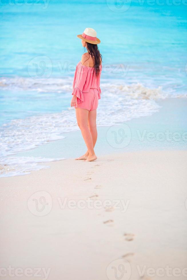 empreintes de pas humaines sur la plage de sable blanc avec une belle jeune femme en arrière-plan photo