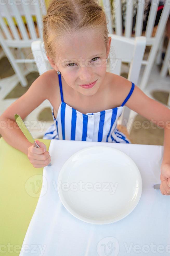 adorable petite fille prenant son petit déjeuner au café d'été en plein air photo