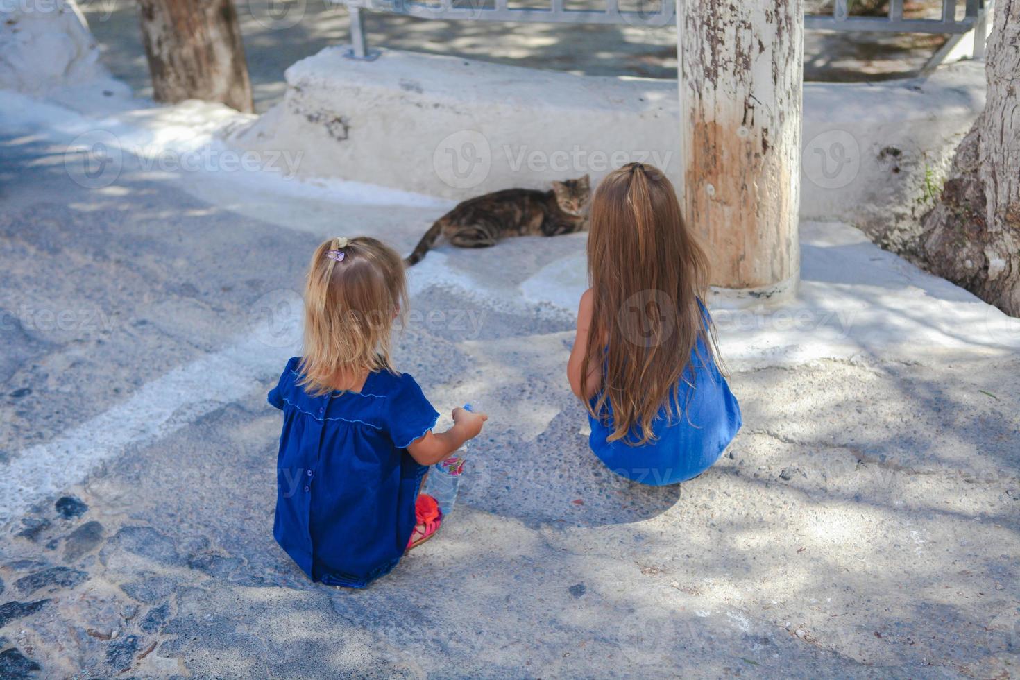 Les petites filles jouent avec un chat dans les rues d'Emporio, Santorin, Grèce photo