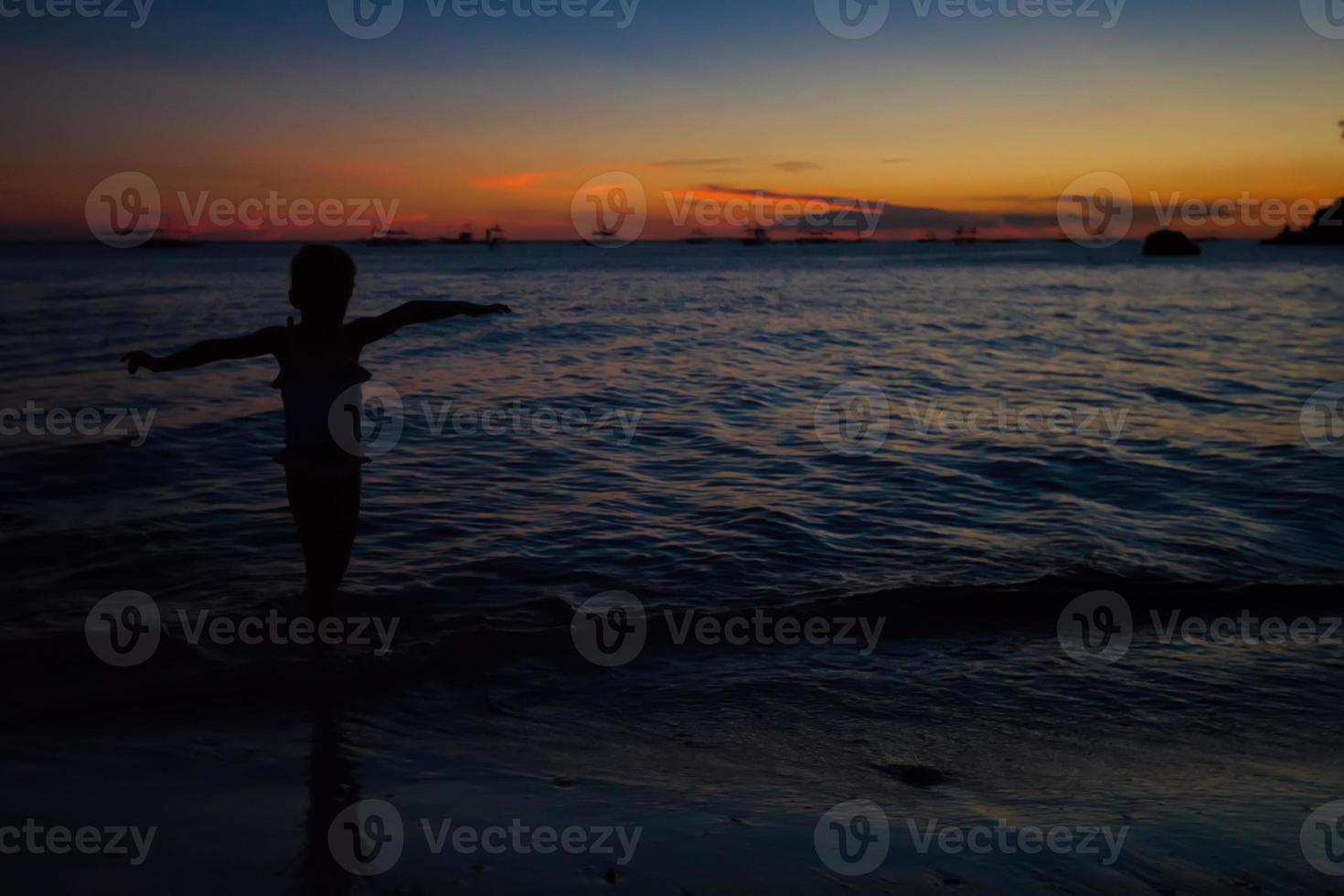 silhouette de petite fille au coucher du soleil sur l'île de boracay, philippines photo