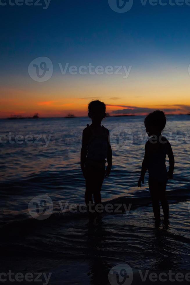 silhouette de deux filles au coucher du soleil sur l'île de boracay, philippines photo