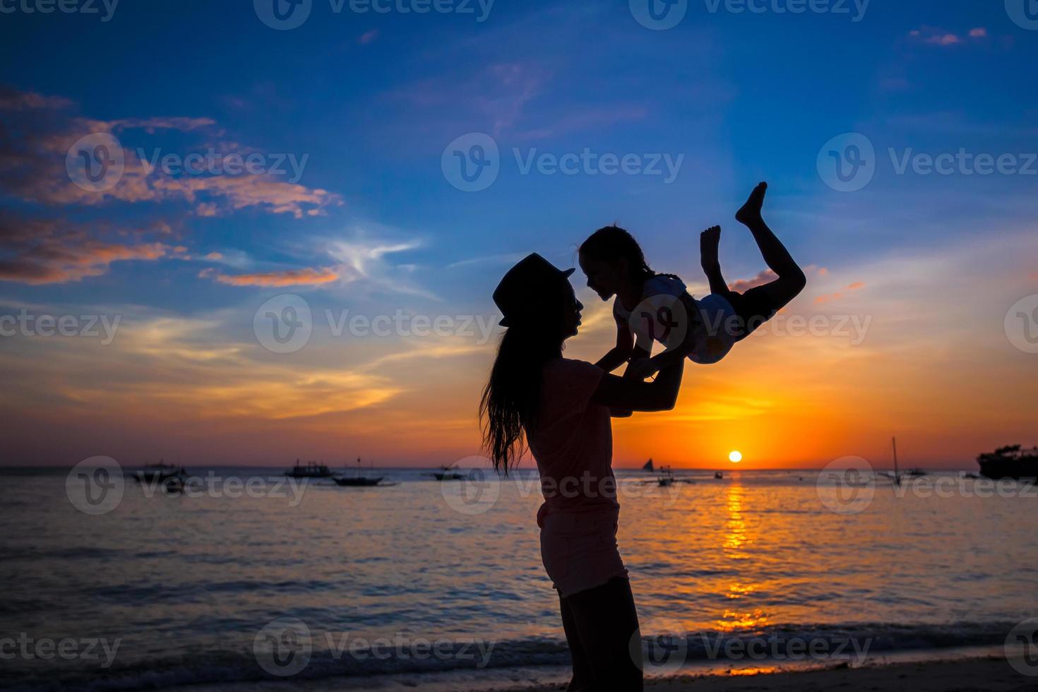 petite fille et sa mère s'amusant au coucher du soleil sur l'île de boracay, philippines photo