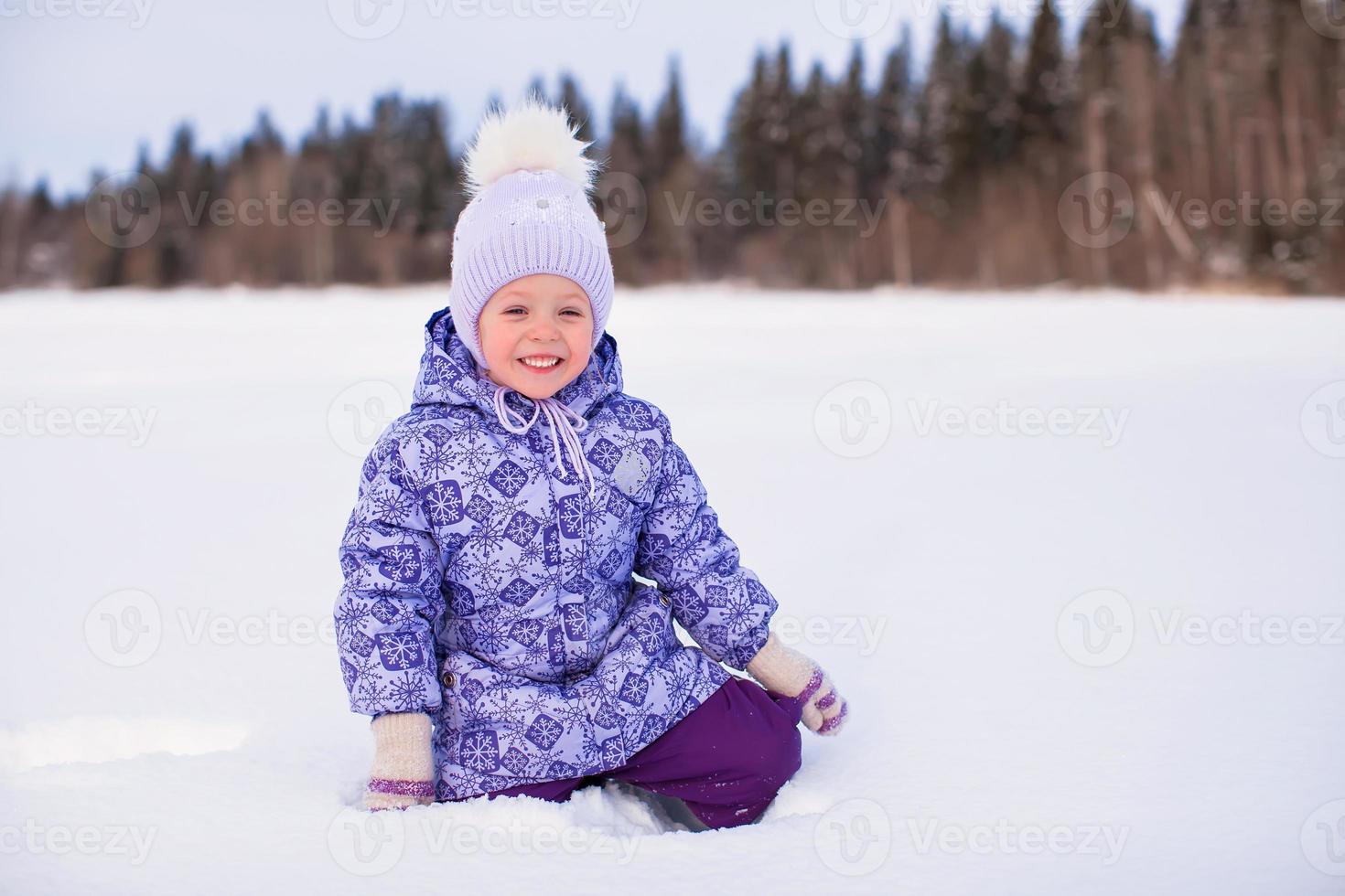 petite fille adorable heureuse s'amusant sur la neige à la journée ensoleillée d'hiver photo