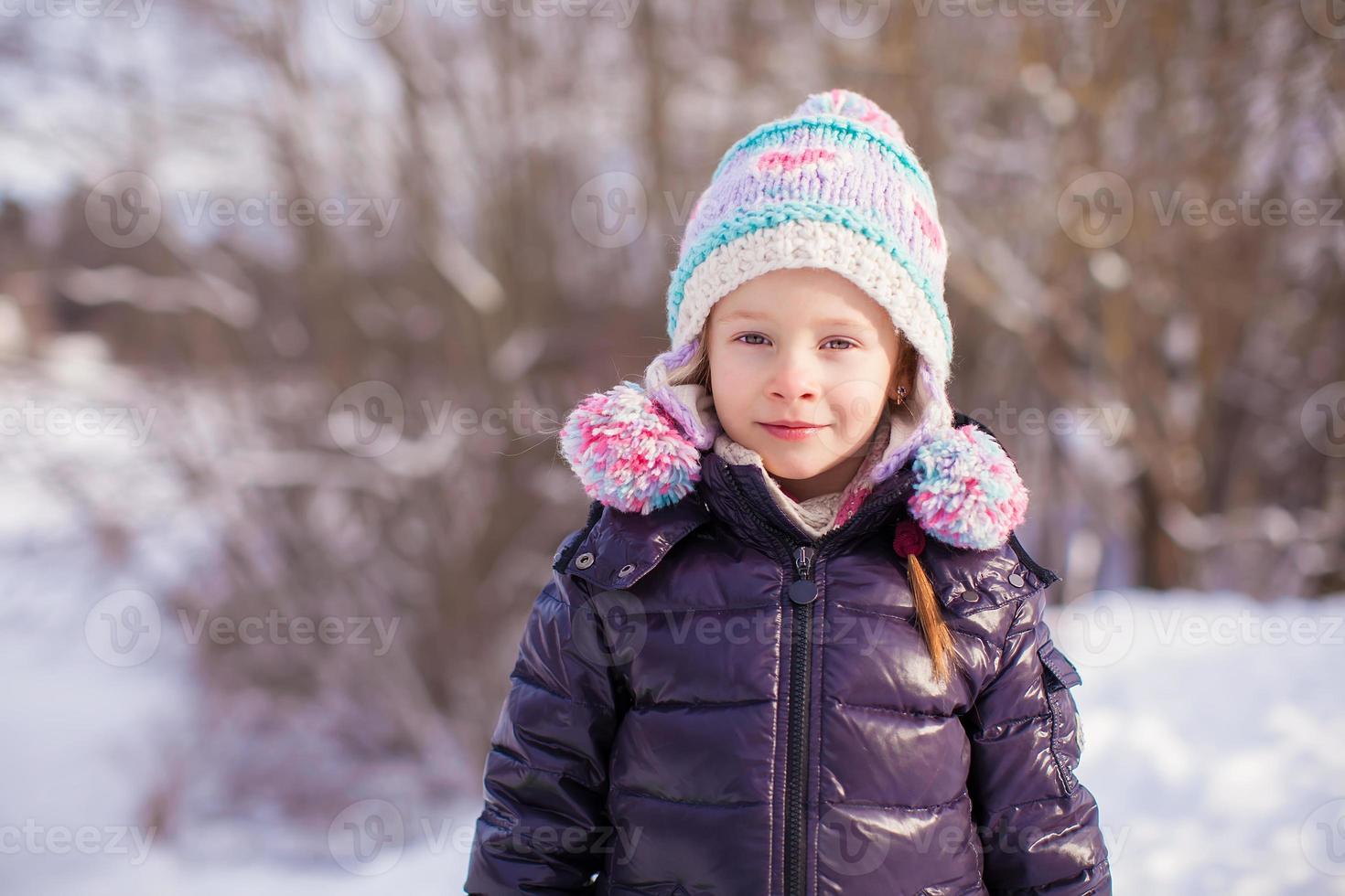 portrait de petite fille adorable en chapeau d'hiver à la forêt enneigée photo