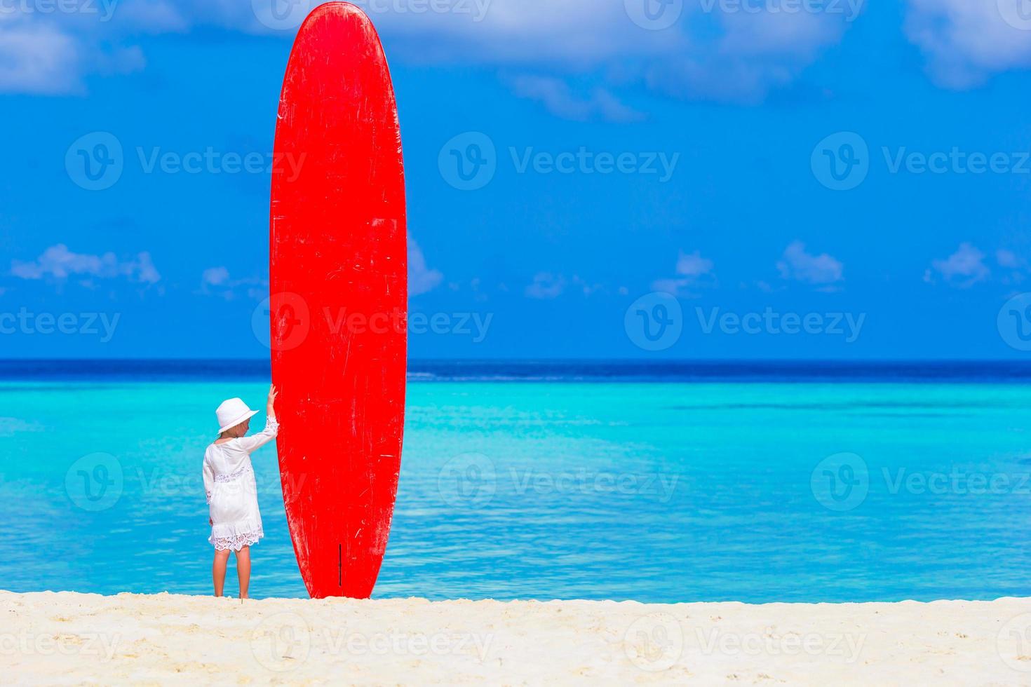 adorable petite fille avec une grande planche de surf pendant des vacances tropicales photo