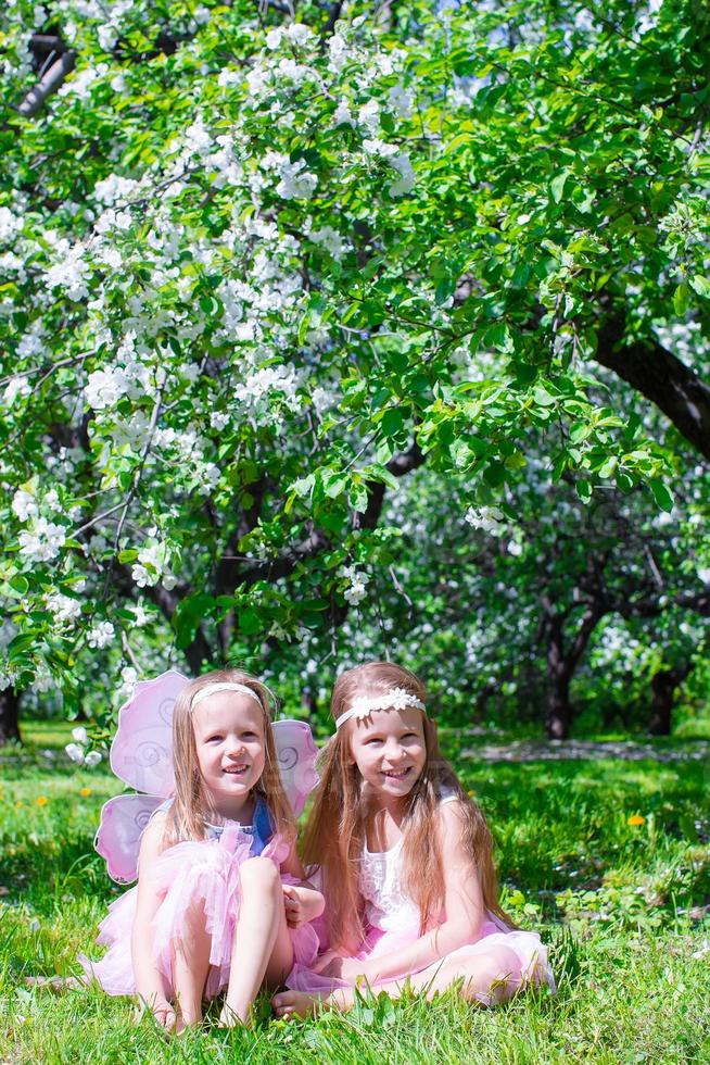 adorables petites filles s'amusent dans un jardin de pommiers en fleurs photo