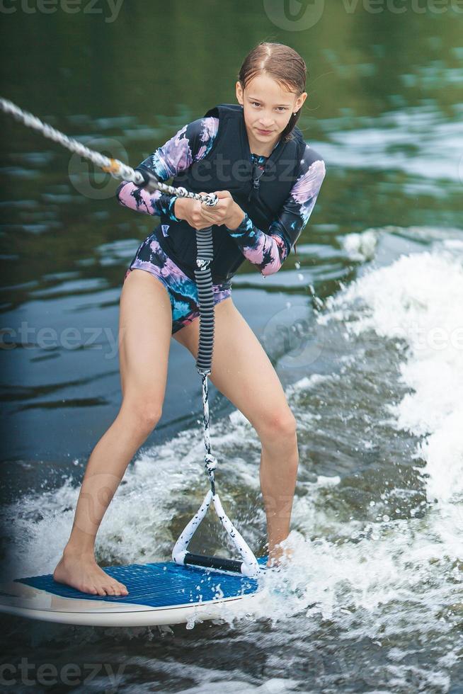 belle fille active en maillot de bain debout sur le wakeboard dans la rivière photo