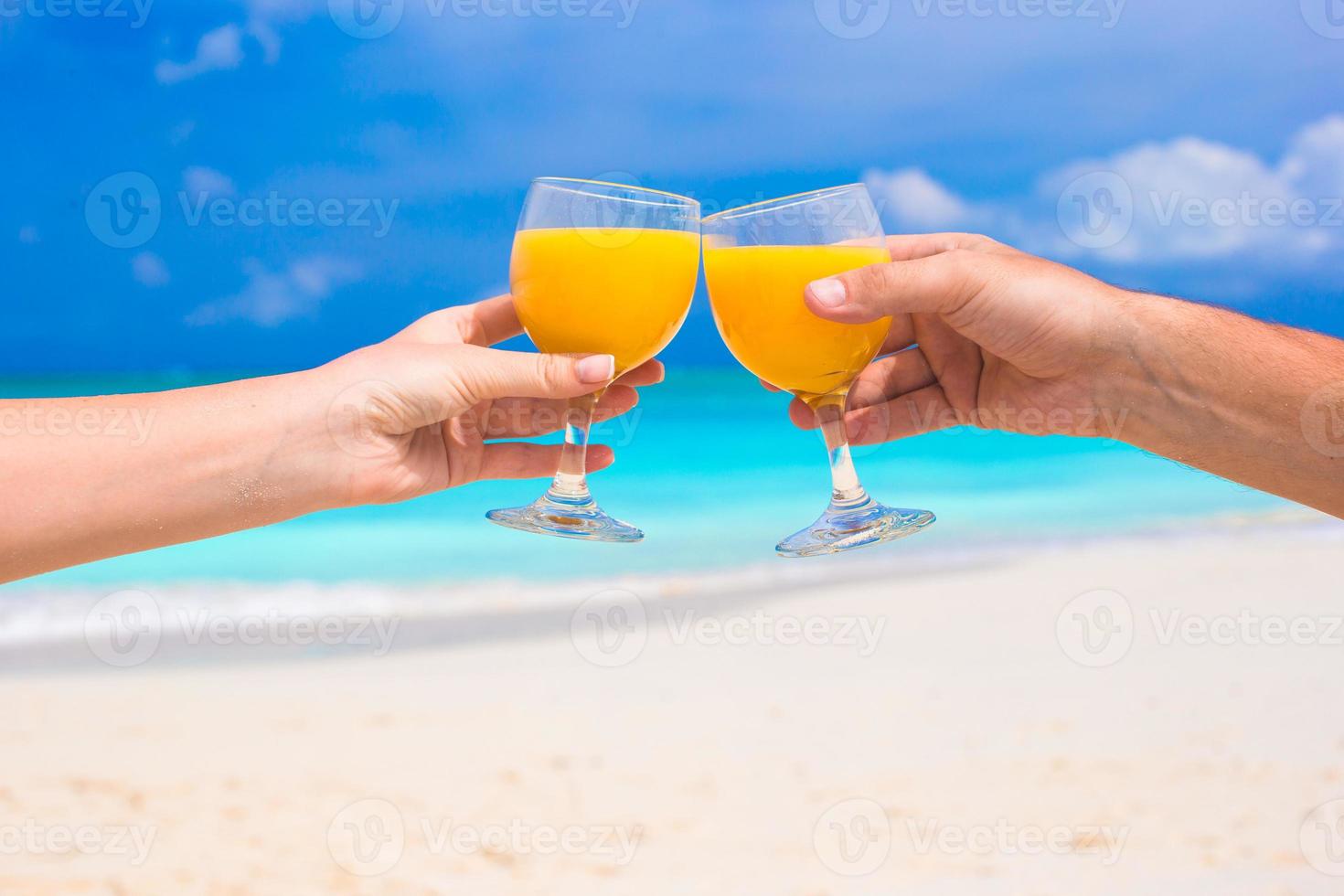 deux mains tiennent des verres avec du jus d'orange fond bleu ciel photo
