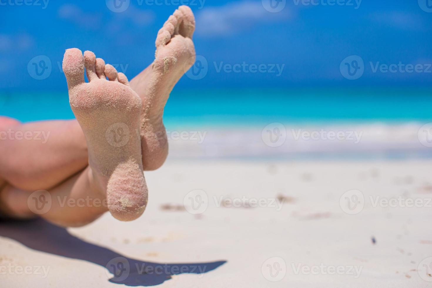 gros plan de pieds féminins sur une plage de sable blanc photo