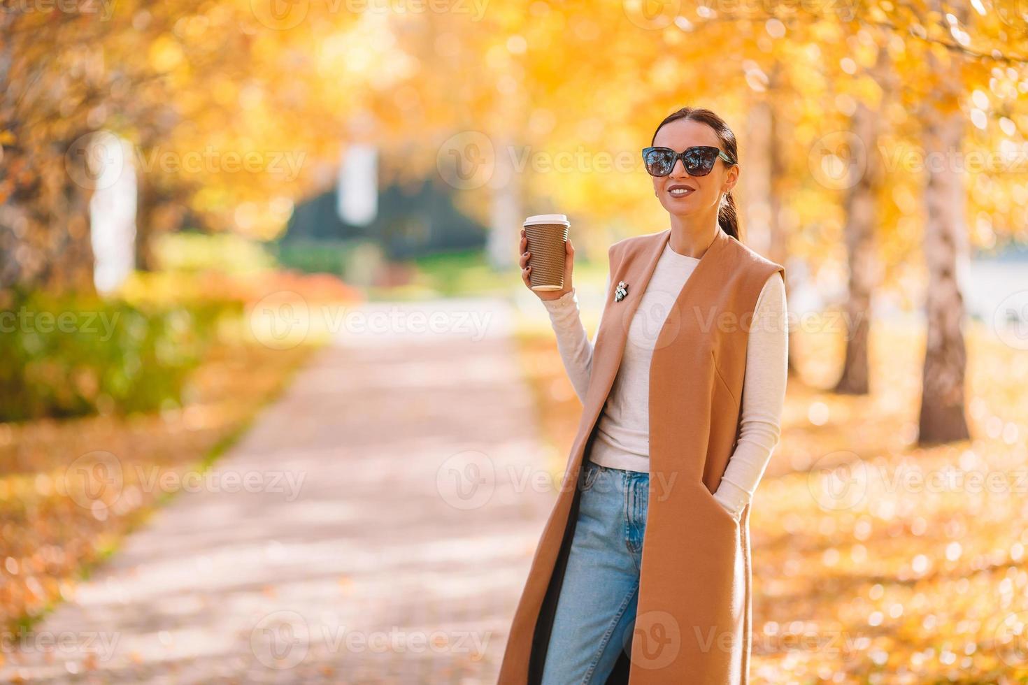 concept d'automne - belle femme buvant du café dans le parc d'automne sous le feuillage d'automne photo