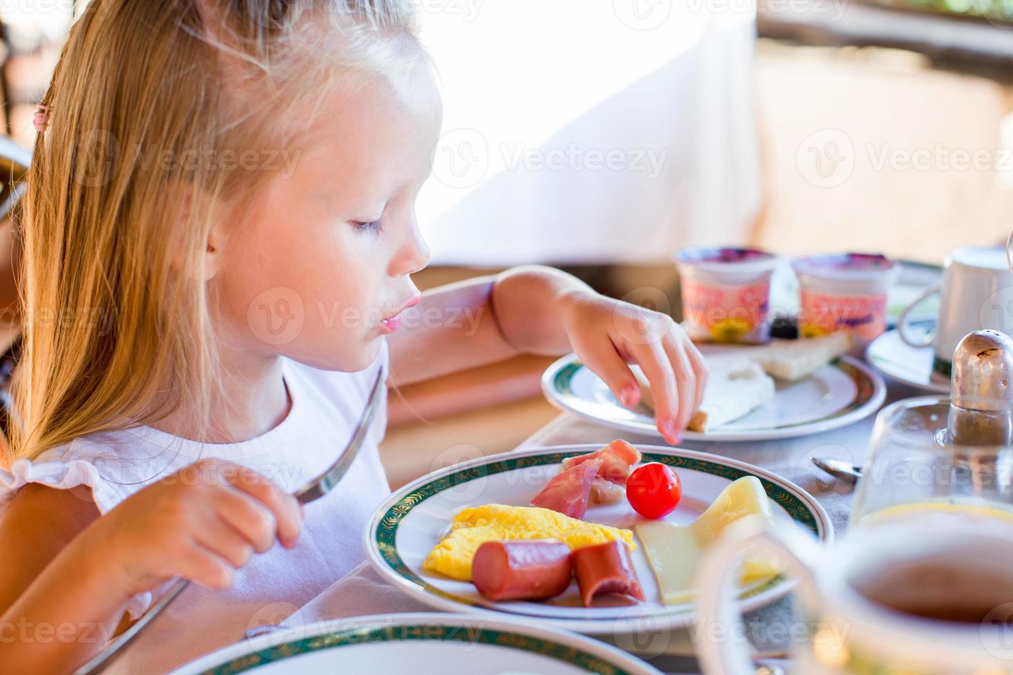 adorable petite fille prenant son petit déjeuner au restaurant photo