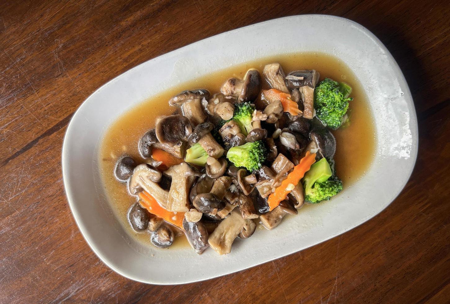 Champignons sautés au légume carotte brocoli, champignons shiitake avec sauce aux huîtres cuisson des aliments sur plaque blanche, champignons shiitake cuits par friture photo