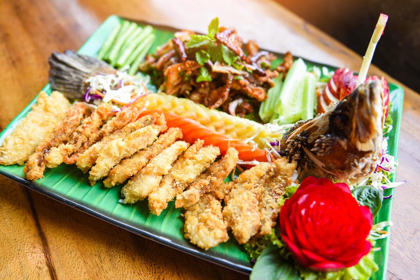 Filet de poisson de bar des aliments cuits style thaï asiatique - salade de bar poisson frit croustillant décoré sur une assiette servi sur une table en bois dîner alimentaire photo