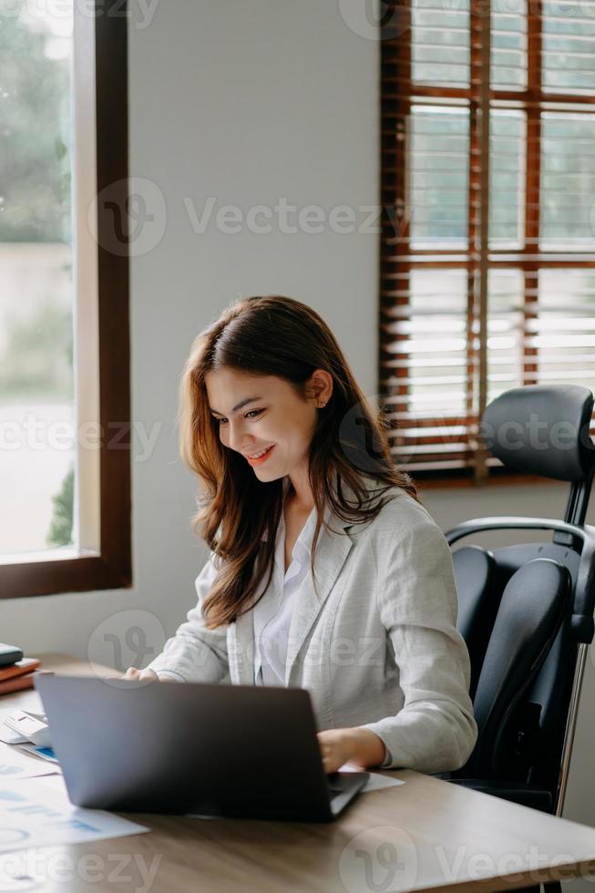 femme asiatique confiante avec un sourire debout tenant un bloc-notes et une tablette au bureau. photo