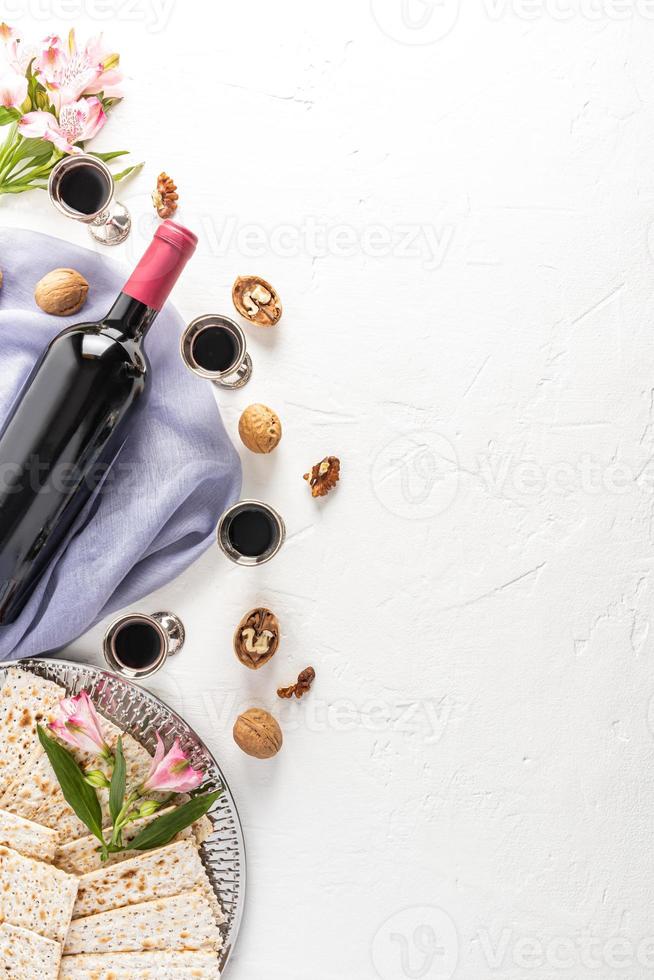un fond festif vertical de la pâque juive avec un espace de copie. une bouteille de vin rouge, des verres en argent avec du vin, de la matzah, des noix. photo